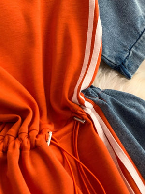 Orange casual dress with drawstring and white stripes, paired with denim.