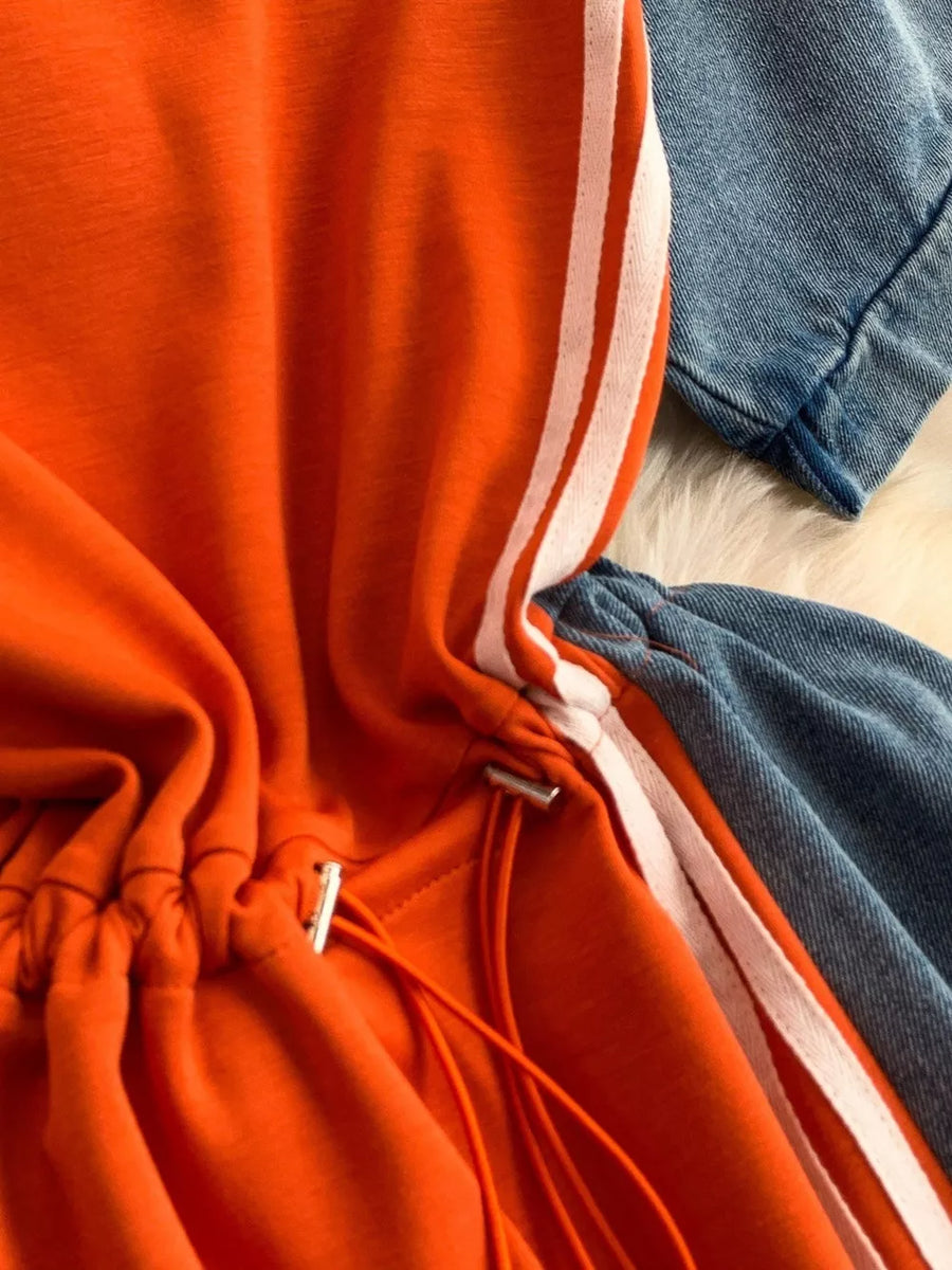 Orange casual dress with drawstring and white stripes, paired with denim.