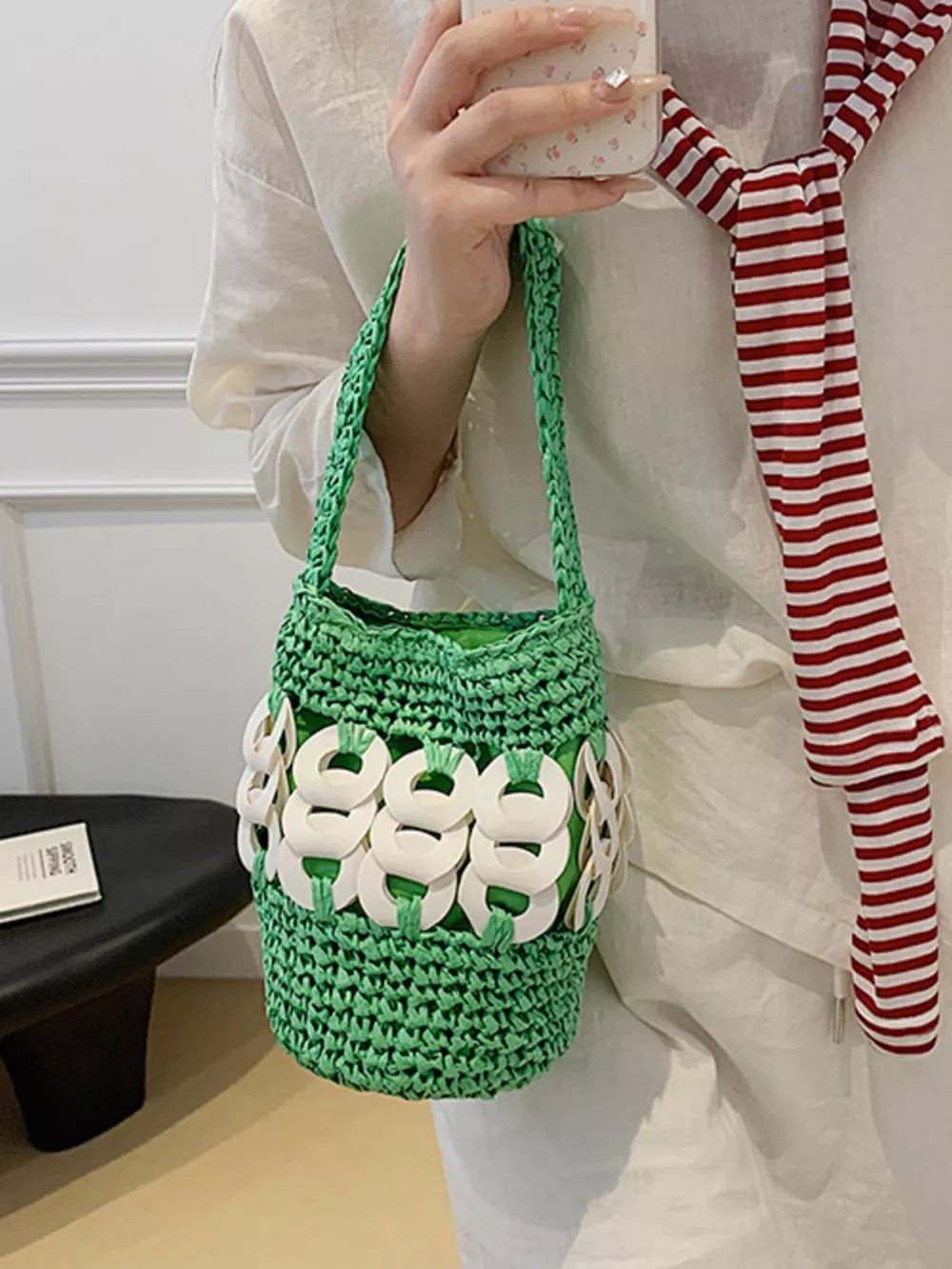 Green woven straw bucket tote with white ring detail and braided strap.