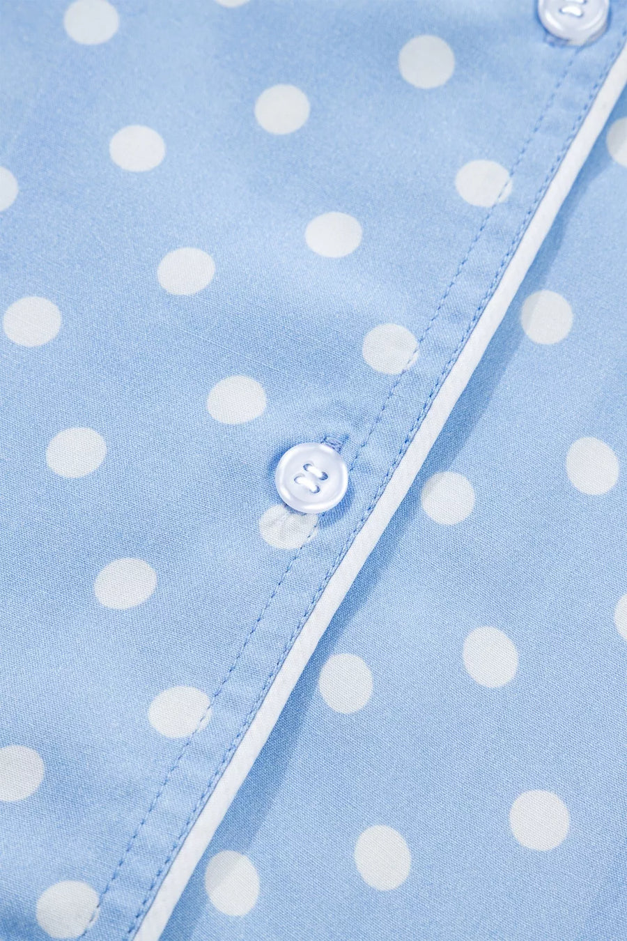 Blue polka dot viscose pajama top with white piping and button detail.