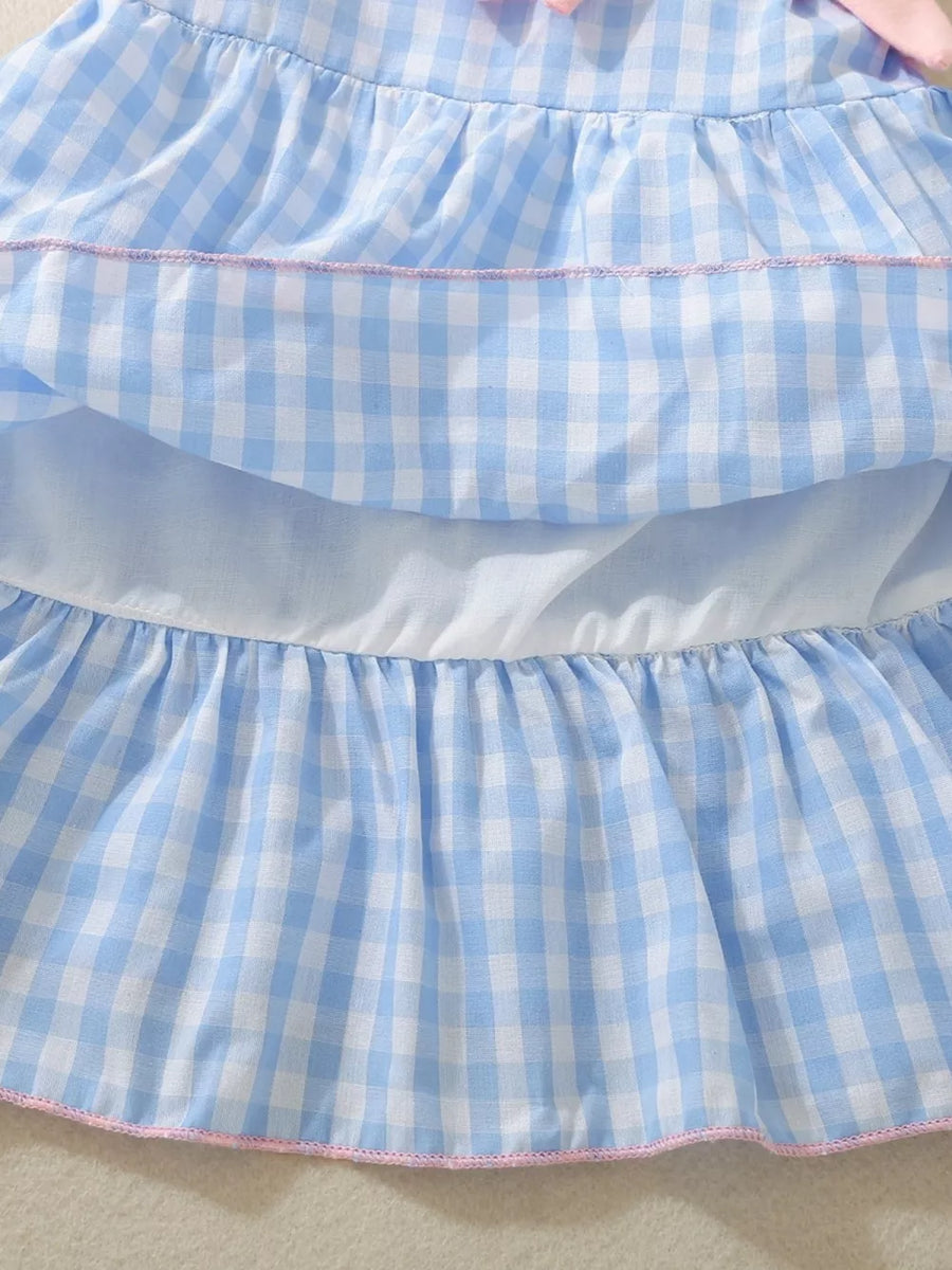 Blue gingham baby dress with ruffles and pink trim, featuring a bow detail.