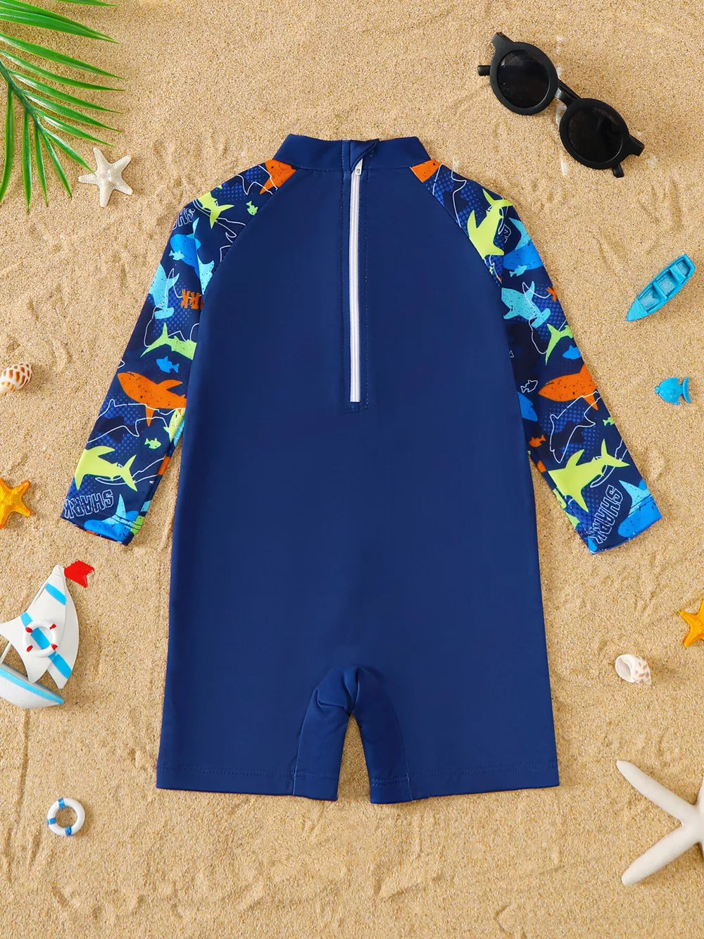 Navy baby rash guard swimsuit with shark print on sleeves and collar.