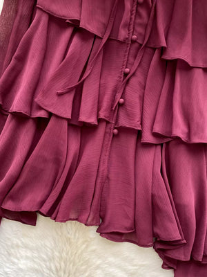 Burgundy chiffon tiered blouse with ruffled details and bow-tie neckline.