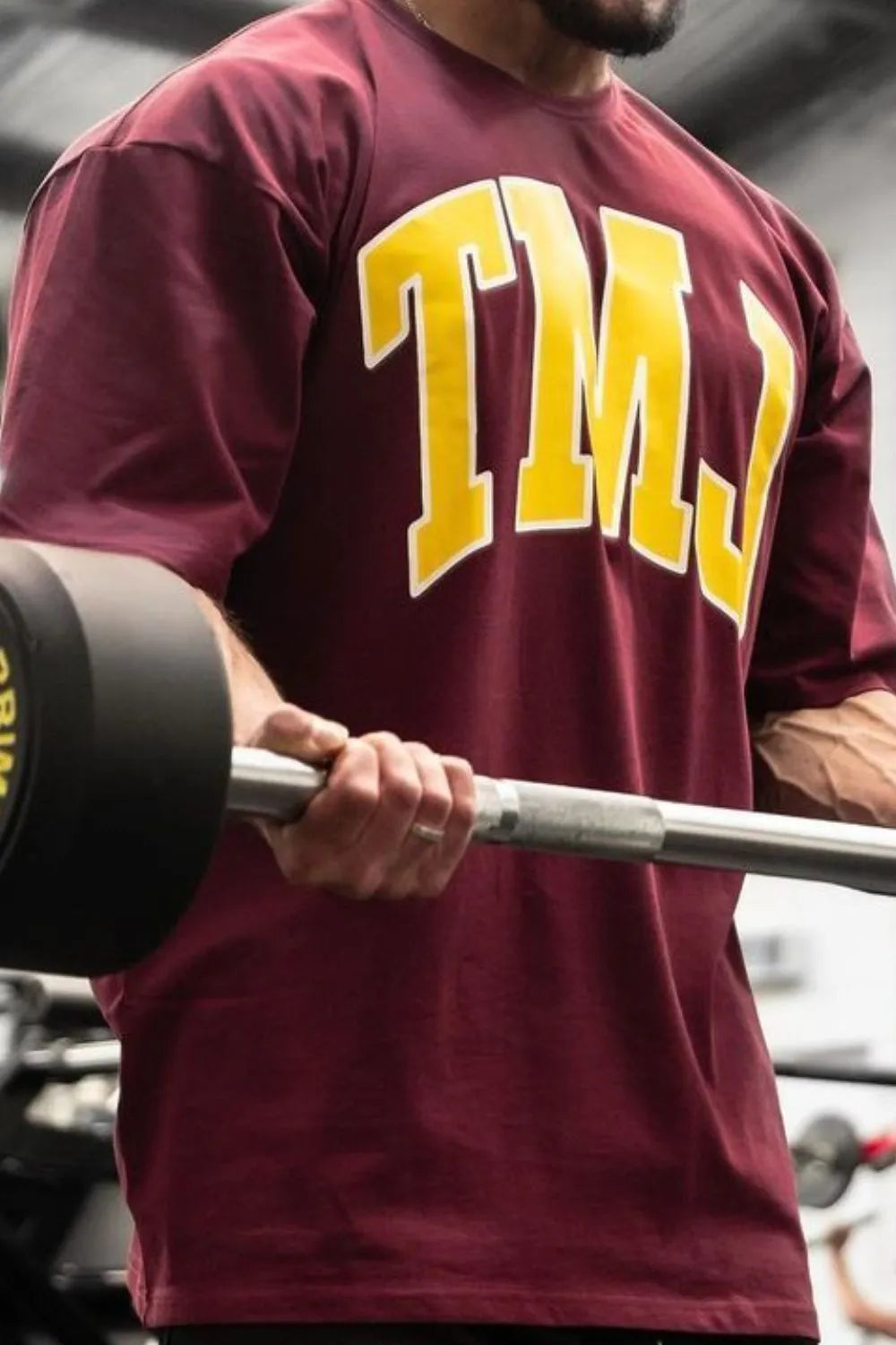 Burgundy oversized graphic tee with yellow TMJ lettering, athletic fit.