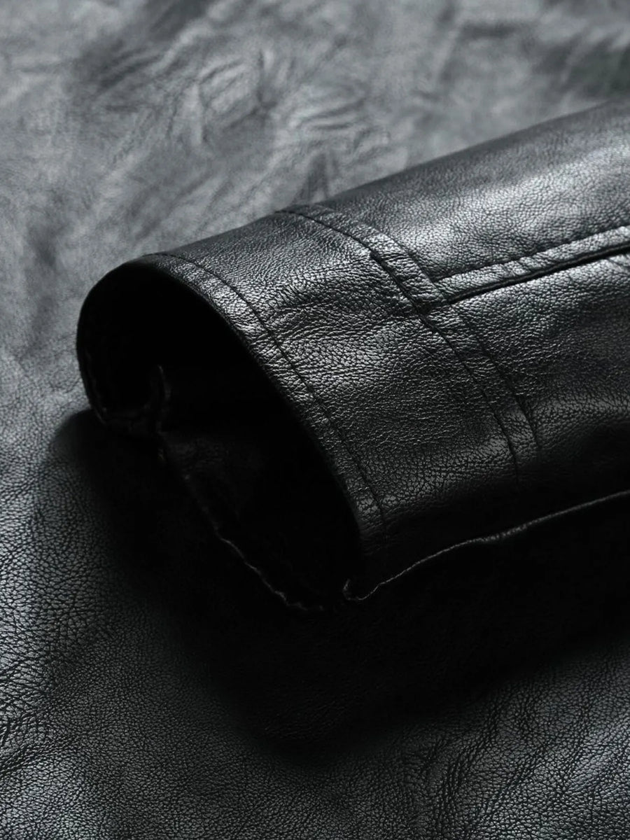 Black moto jacket detail showing textured faux leather and stitching.