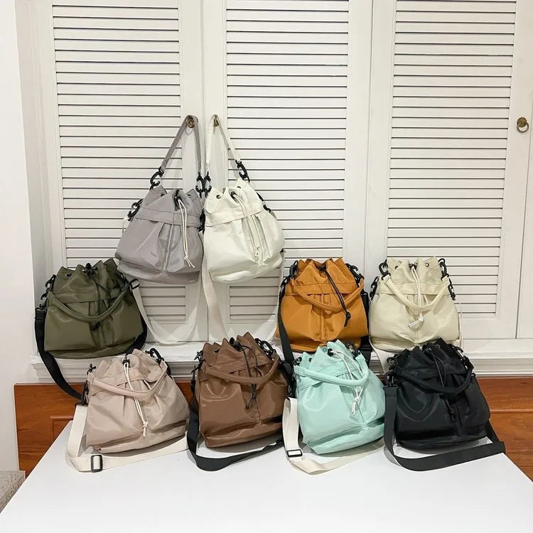 Drawstring nylon bucket bag with chain strap in multiple colors including black, white, and khaki.