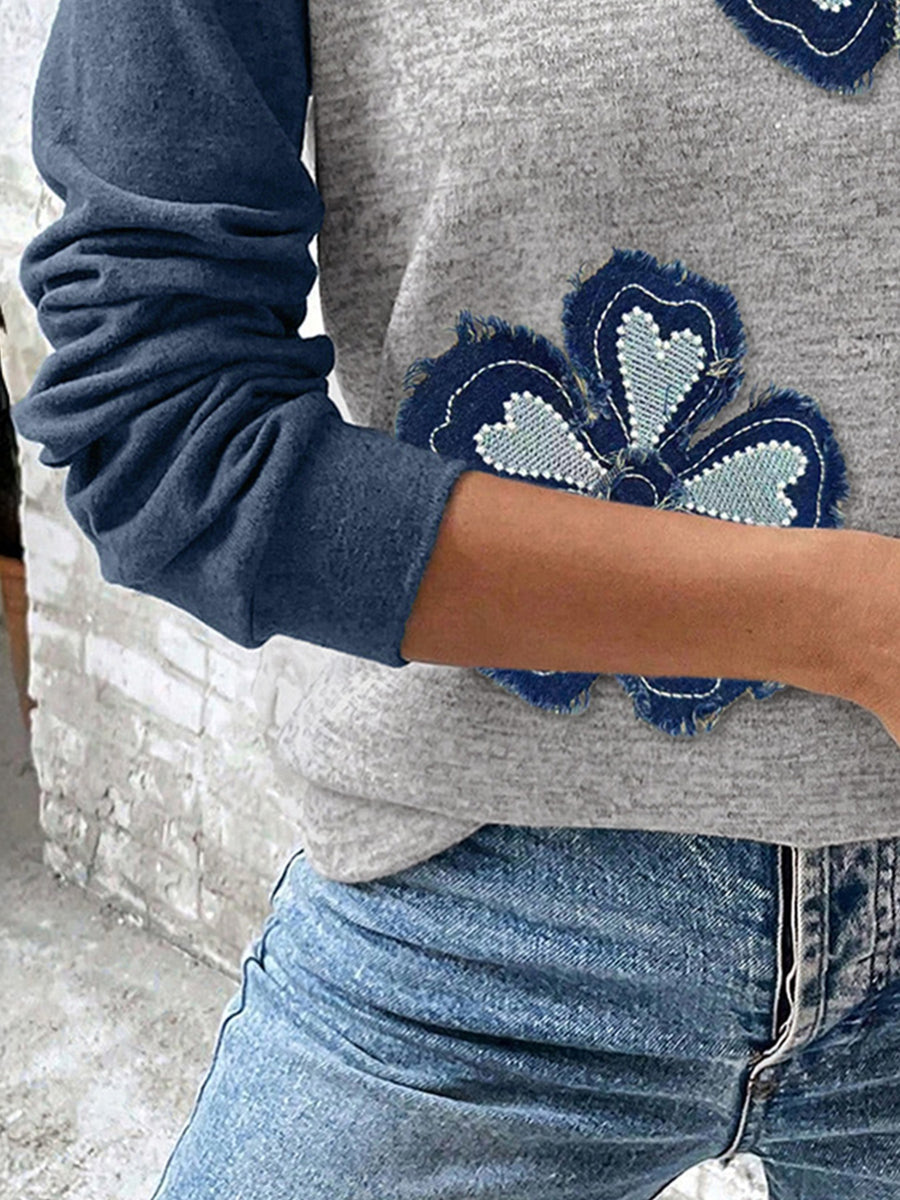 Grey raglan shirt with blue denim embroidered flower patches and navy sleeves.