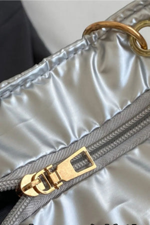 Silver quilted nylon tote bag with gold zipper and chain handle detail.