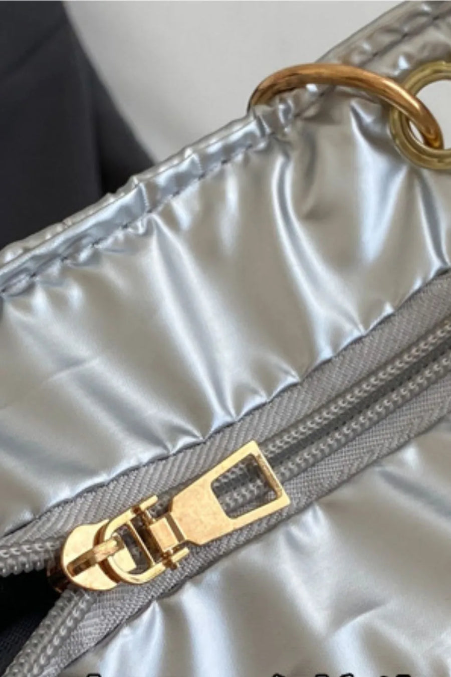 Silver quilted nylon tote bag with gold zipper and chain handle detail.