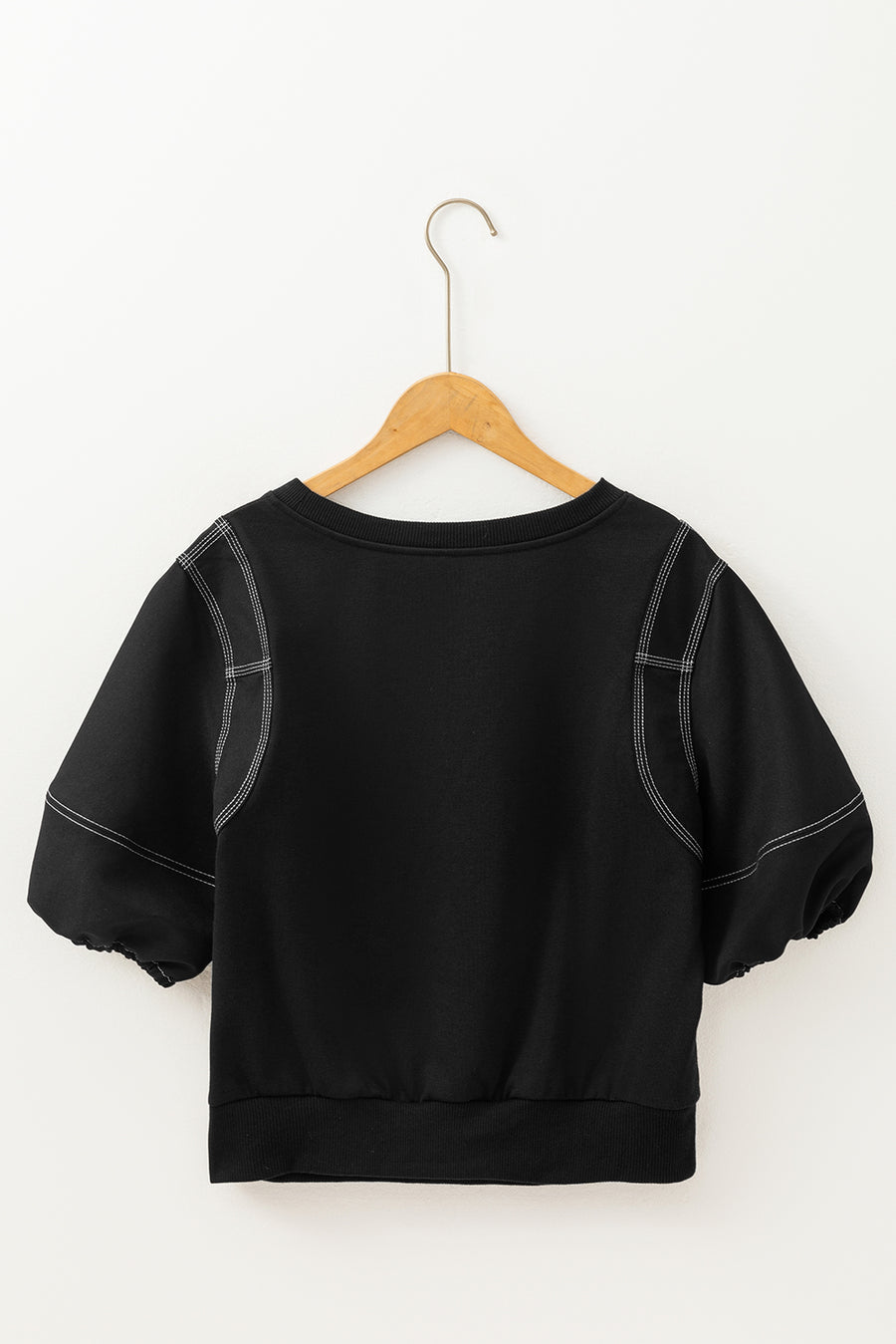 Black blouse with contrast stitching, puff sleeves, and a crew neck.