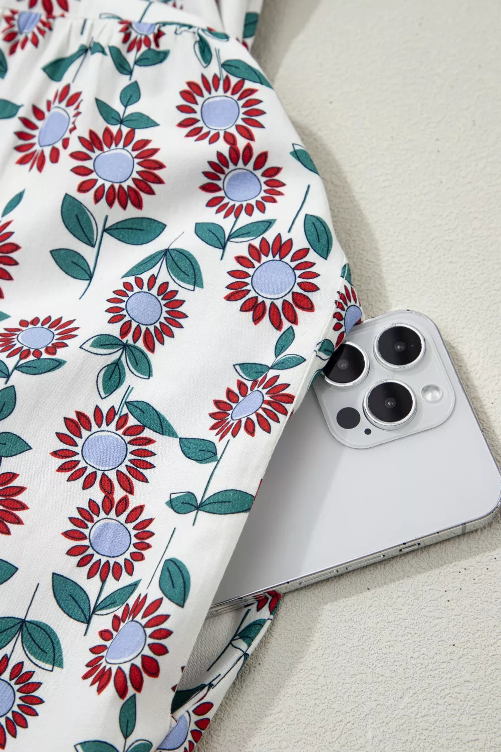 Vibrant floral midi dress in white cotton with red and blue flowers, showing a side pocket detail.