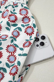 Vibrant floral midi dress in white cotton with red and blue flowers, showing a side pocket detail.