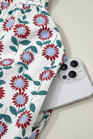 Vibrant floral midi dress in white cotton with red and blue flowers, showing a side pocket detail.