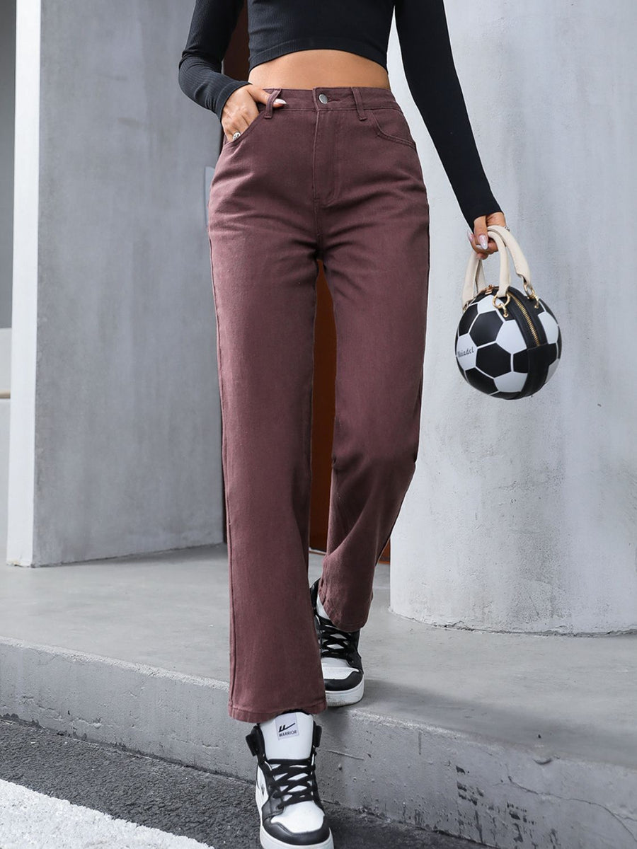 Relaxed straight leg jeans in dark brown with a buttoned fly, styled with sneakers and a soccer ball bag.