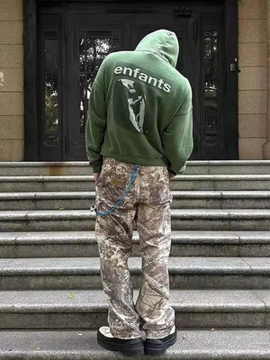 Distressed camo carpenter jeans with blue chain detail and cargo pockets.