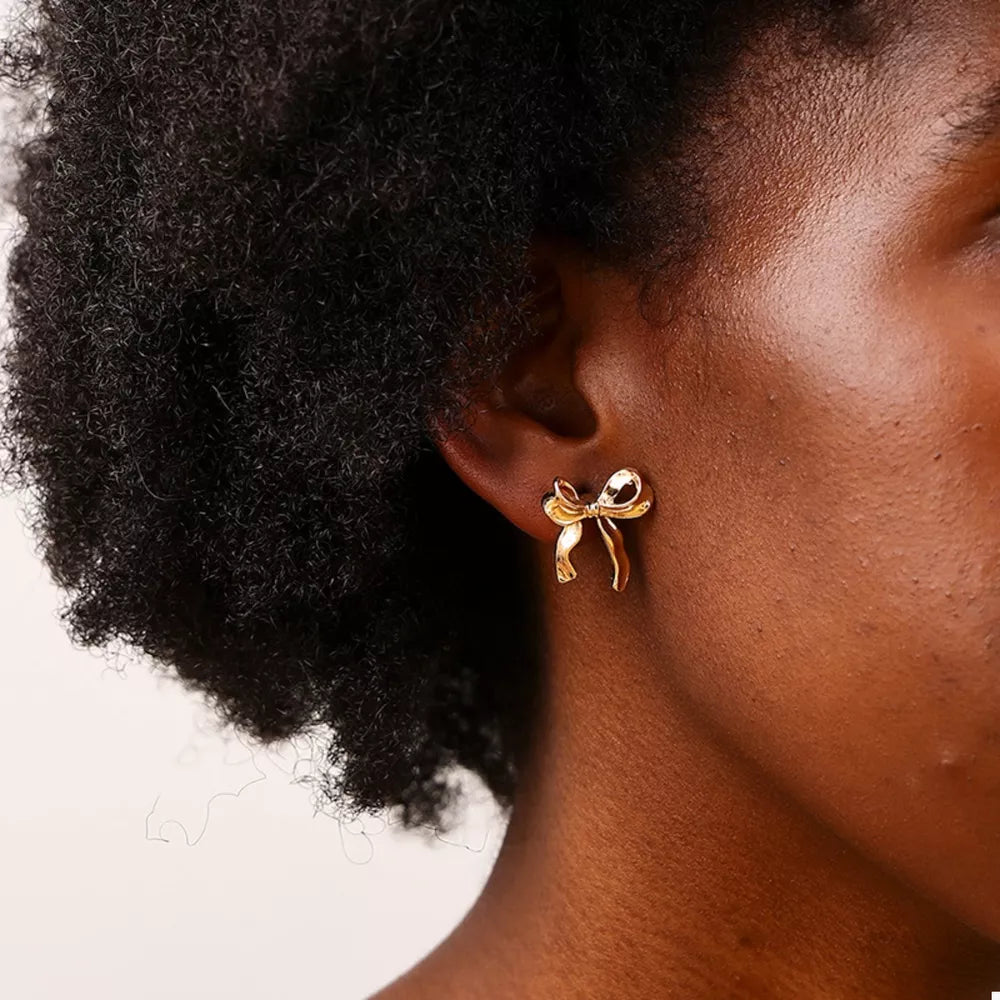 earrings in gold featuring bow design and stud fit
