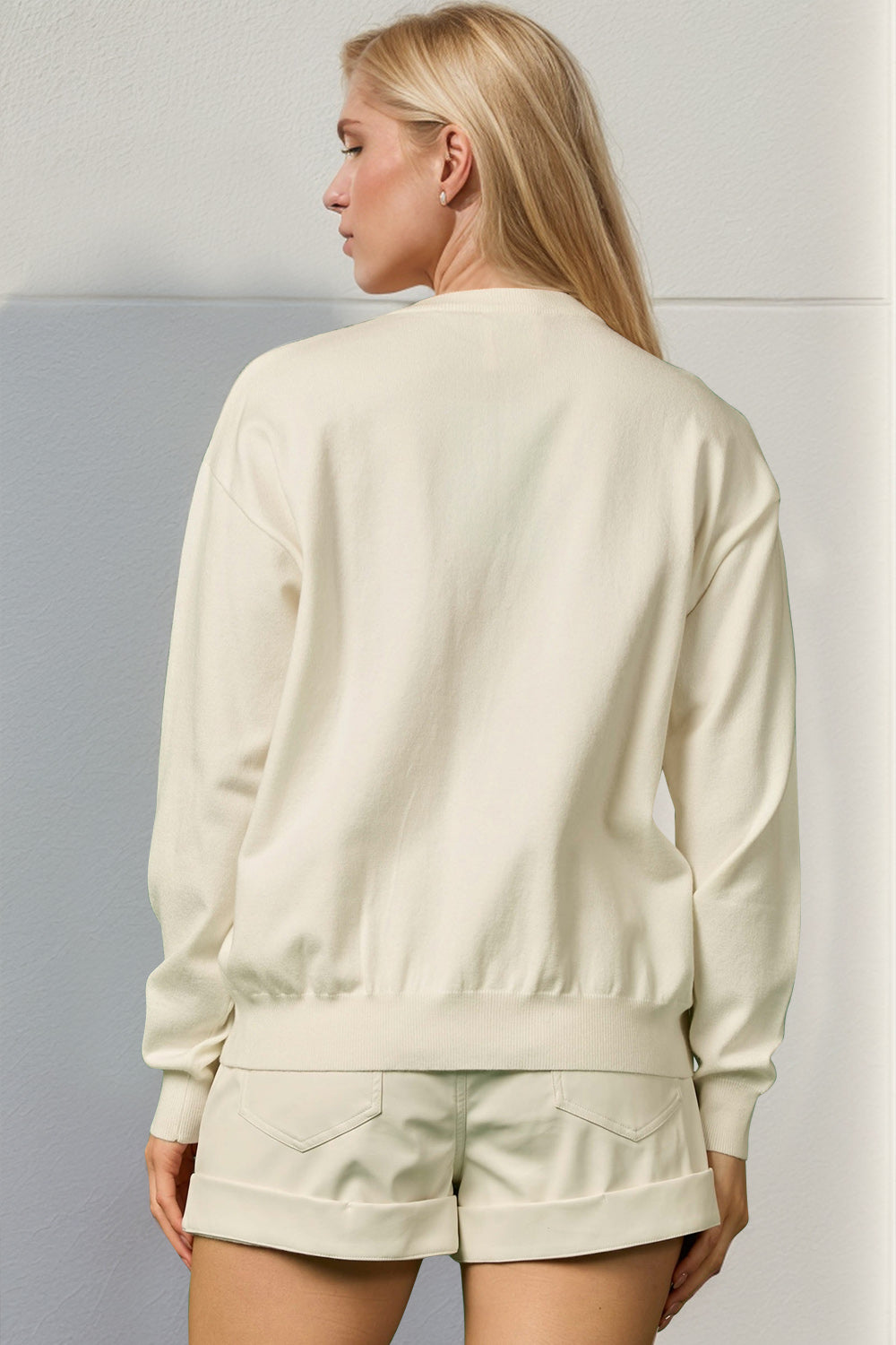 Cream knit crewneck sweater with long sleeves and ribbed trim, 100% polyester.