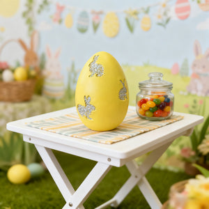 Yellow Easter egg decor with glitter bunny cutouts and a checkered napkin.