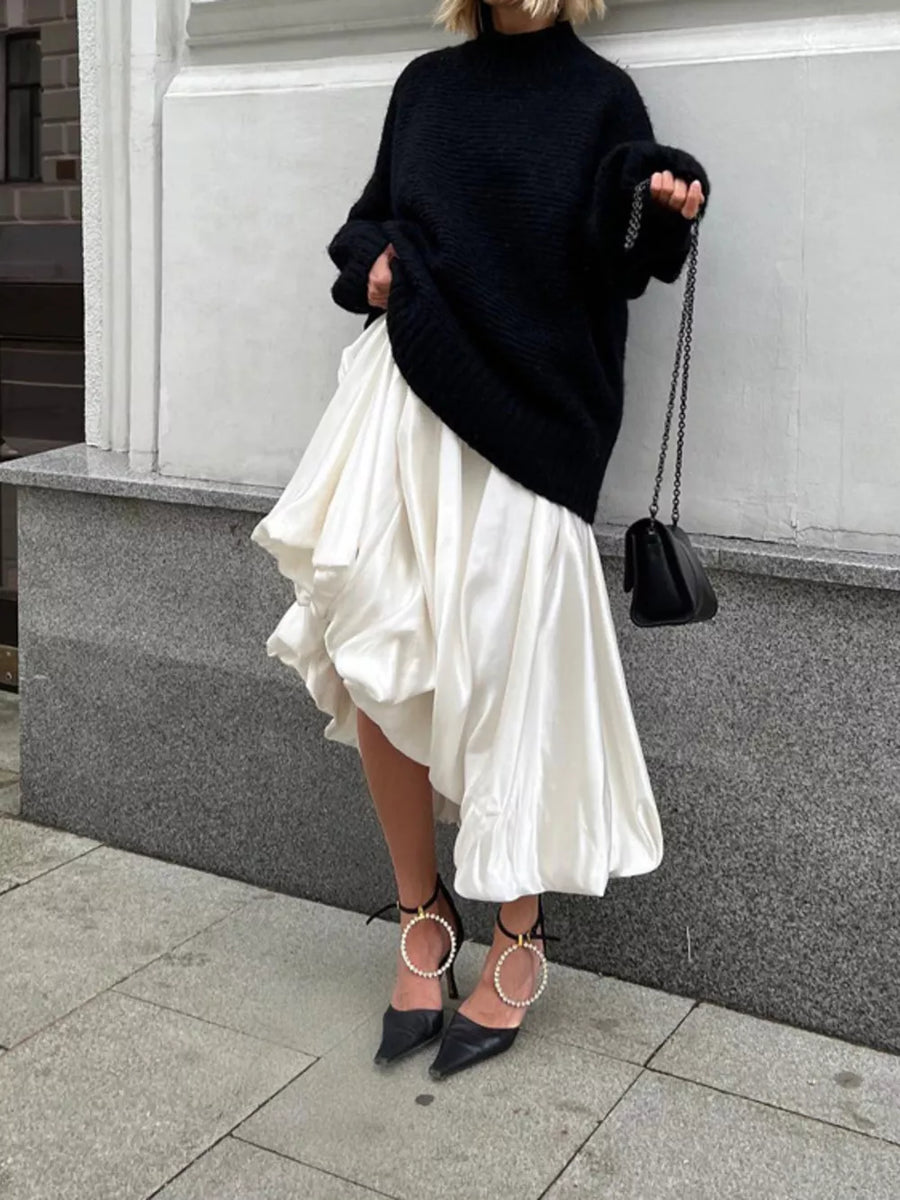 Black oversized sweater with white voluminous midi skirt and black heels with pearl details.