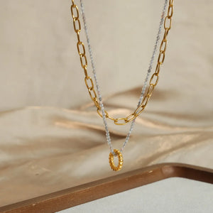 Gold layered chain and beaded pendant necklace with a textured ring detail.