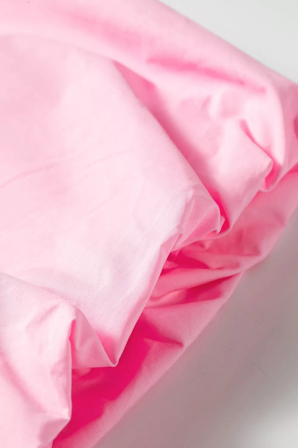 Pink cotton shirt fabric with subtle texture, showing puff sleeve detail.