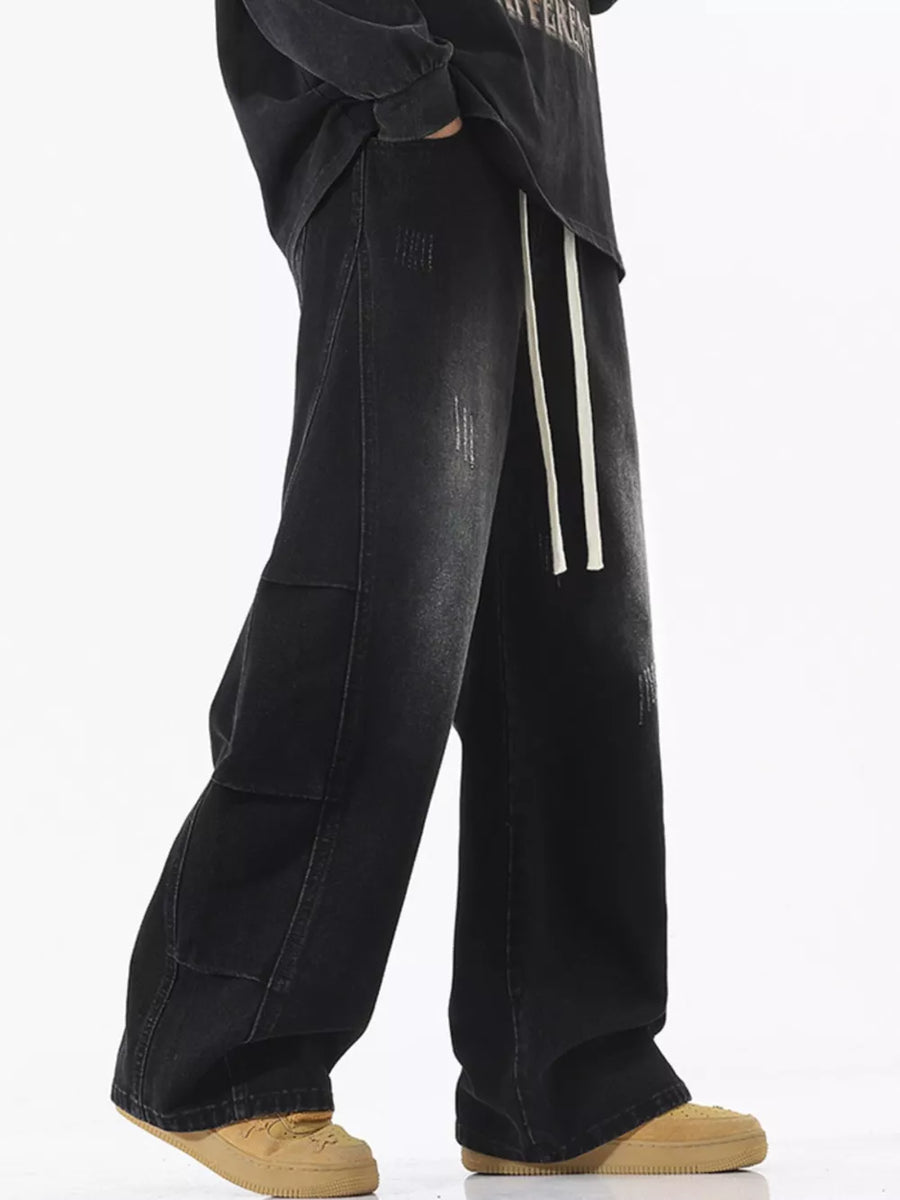 Oversized black vintage wash wide leg jeans with distressed details and drawstring waist.