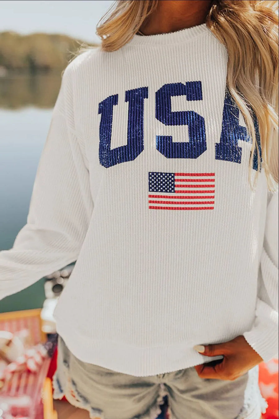 White ribbed knit sweatshirt with blue USA graphic and American flag detail.