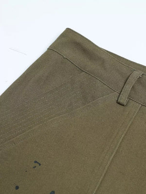 Olive green cotton cargo pants with black paint splatter detail and button fly.