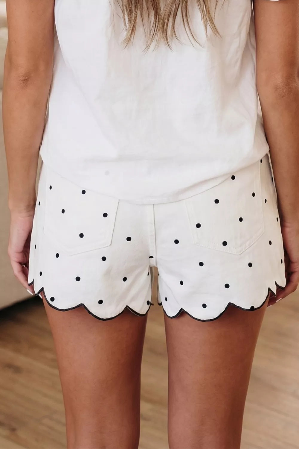 White polka dot chino shorts with black scalloped hem detail.