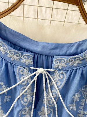Blue tie-neck blouse with intricate white embroidery and balloon sleeves.