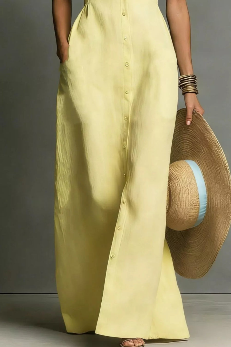 Pastel yellow sleeveless maxi dress with button front and pockets, shown with a straw hat.