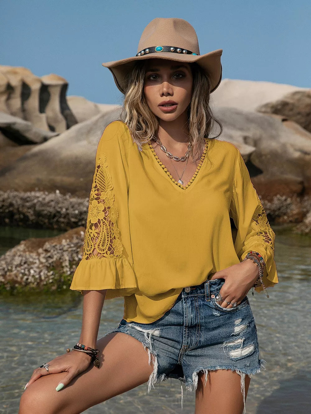 Mustard V-neck blouse with lace bell sleeves and ruffled cuffs.