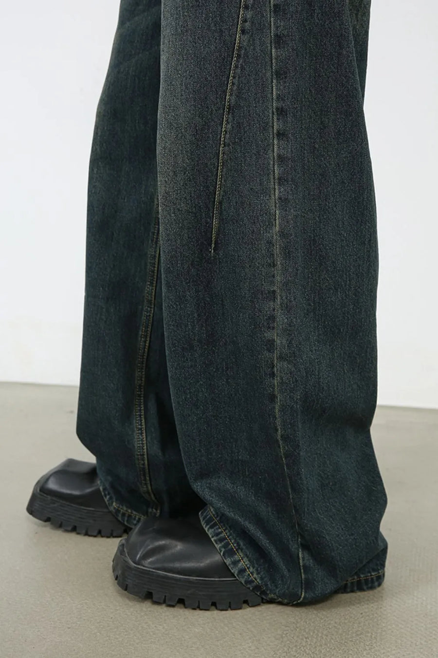Faded dark denim wide-leg trousers with visible stitching detail.