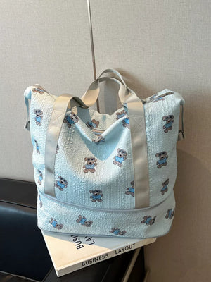 Light blue textured tote bag with allover teddy bear print and grey straps.
