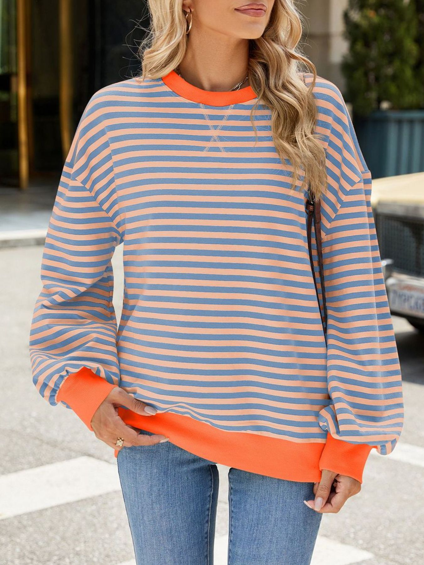 Striped crew neck sweatshirt with orange cuffs and hem, featuring blue and coral stripes.