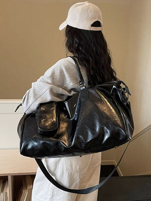 Black sleek metallic large travel bag with adjustable strap and front pocket detail.