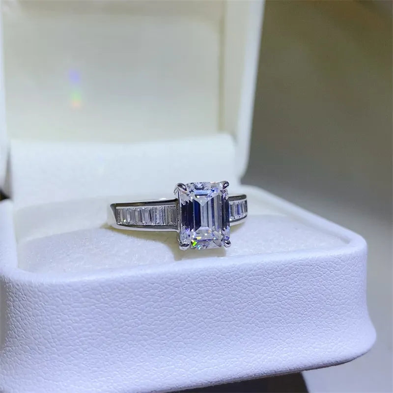 Emerald cut moissanite ring with baguette accents in silver.