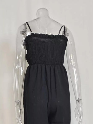 Black smocked wide leg romper with spaghetti straps and ruffled neckline.