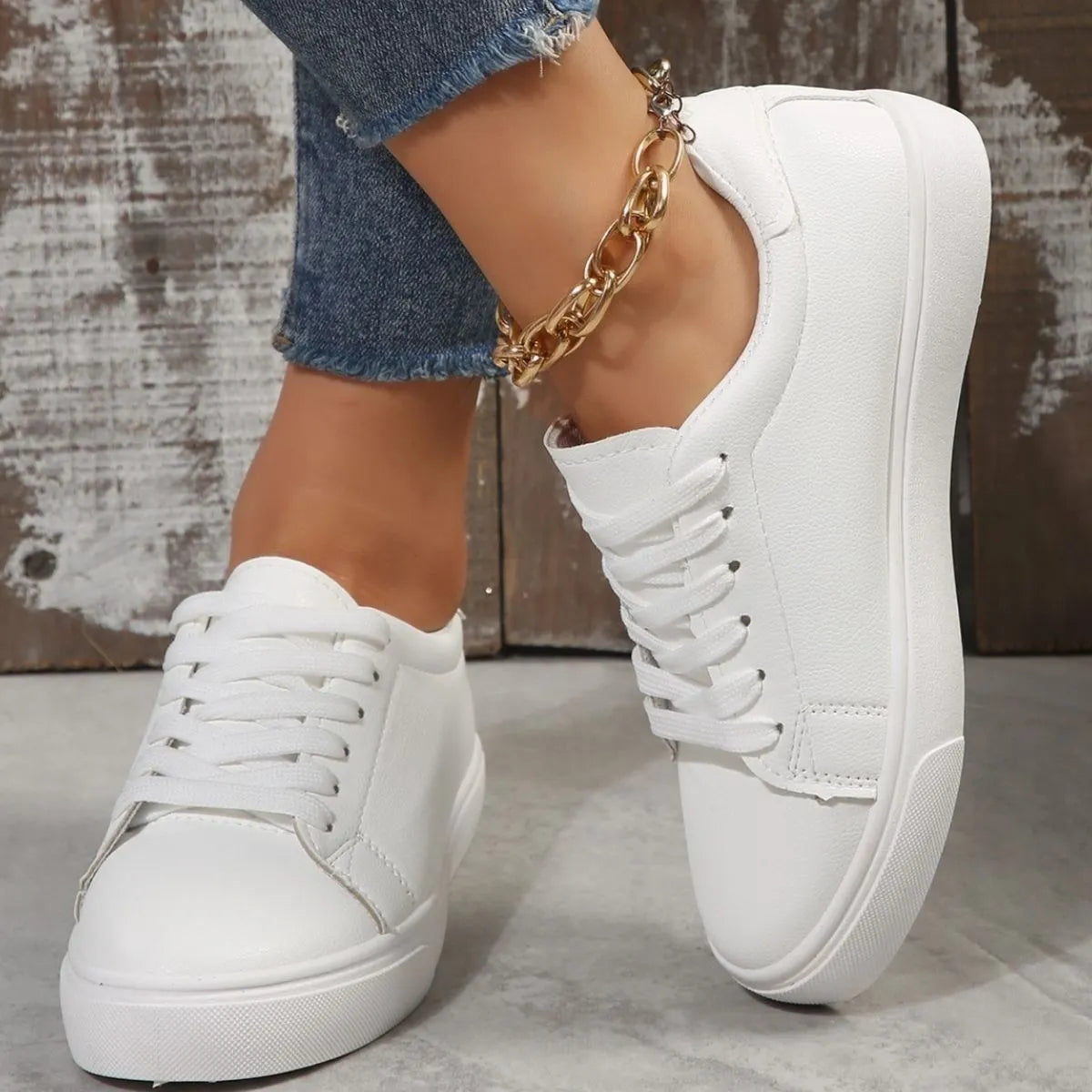 White leather-look platform sneakers with lace-up closure and gold chain anklet.