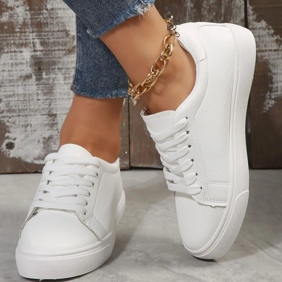 White leather-look platform sneakers with lace-up closure and gold chain anklet.