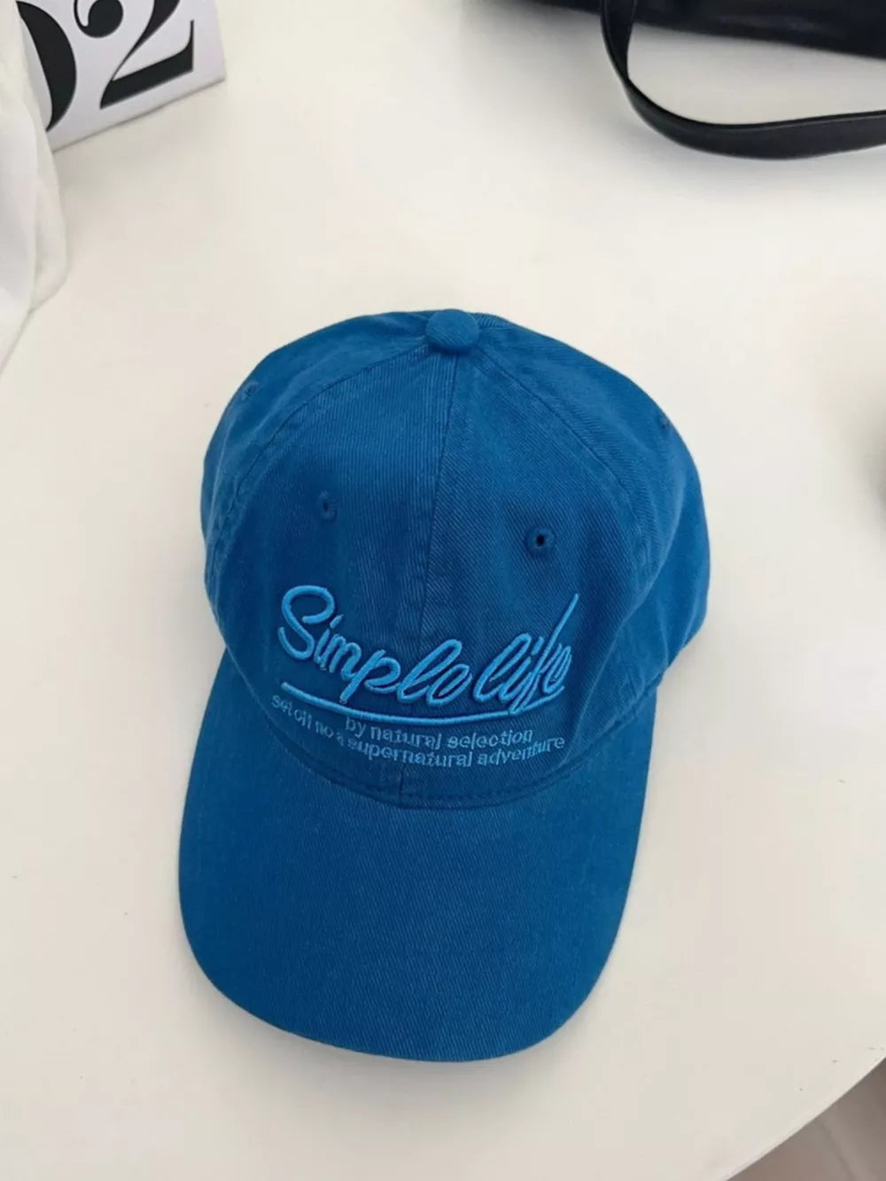Royal blue cotton baseball hat with cursive "Simple Life" embroidery and text detail.