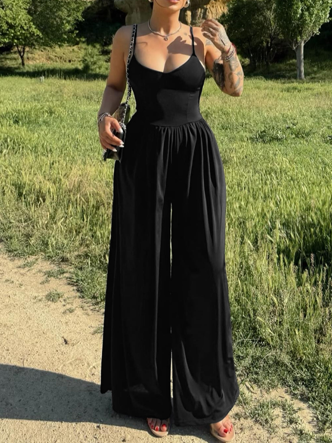 Black crossover back palazzo jumpsuit with spaghetti straps and wide legs.
