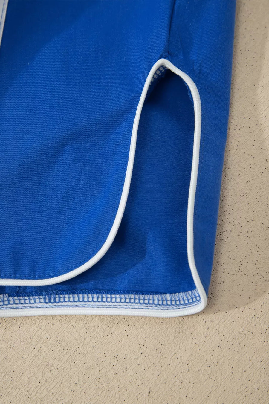Blue maternity cropped pants with white piping detail on the hem and side slit.
