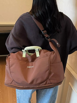 Brown Oxford cloth travel duffel bag with light green handles and side pockets.