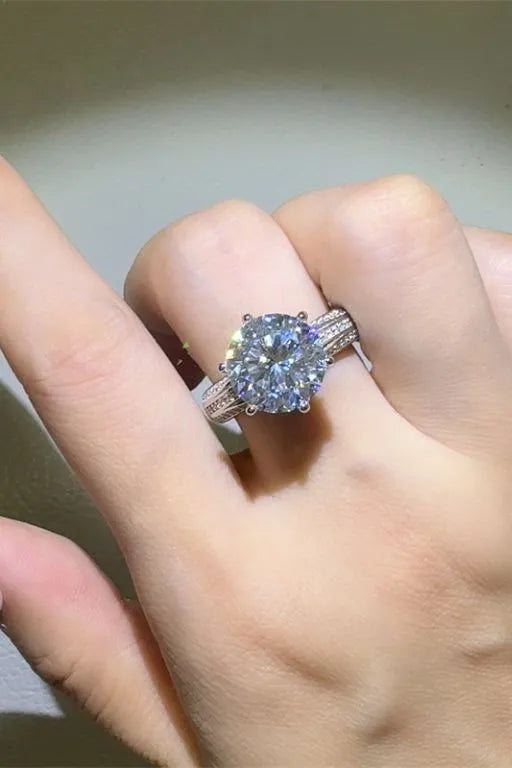 Silver moissanite ring with a large round center stone and pave band.