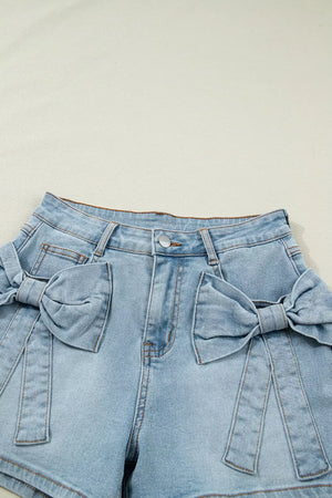 Light wash denim shorts with bow embellishments and button fly.