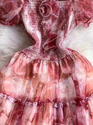 Floral midi dress with smocked bodice and ruffled trim in a pink watercolor print.