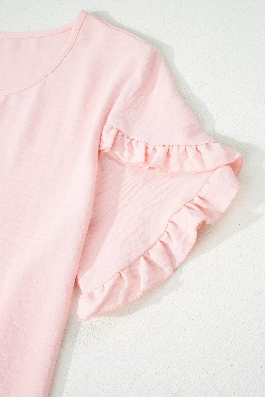 Blush pink polyester blouse with short ruffled sleeves and a crew neck.