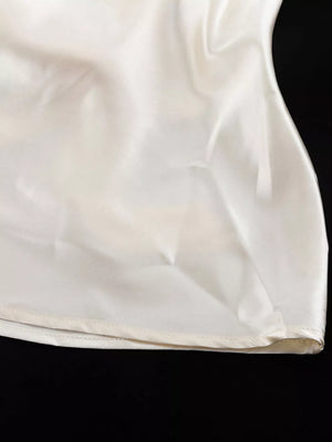 Cream satin camisole with a subtle sheen and a finished hem.
