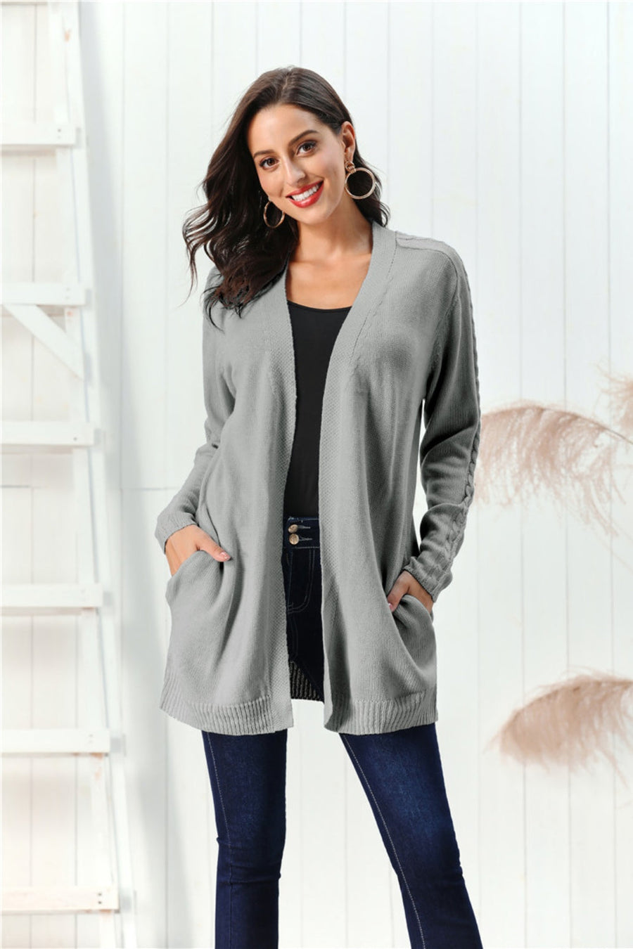 Gray cable knit open front cardigan with pockets and braided sleeve detail.
